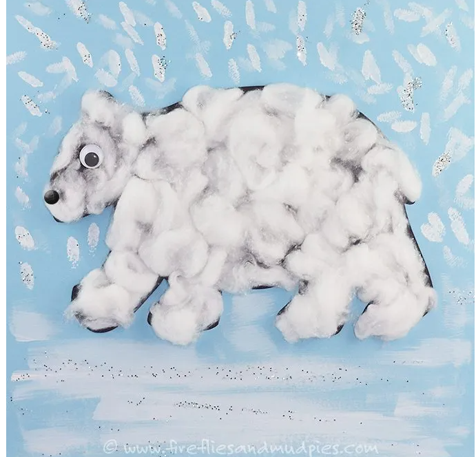 Photo of polar bear craft featuring white bear with cotton balls on blue paper.