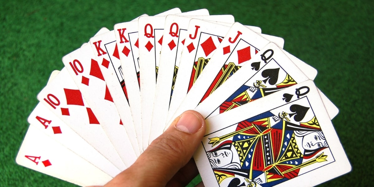Hand holding fanned pinochle cards.