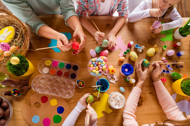 Overhead view of children around a table decorating eggs.