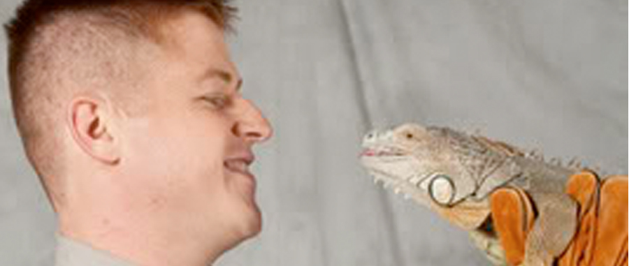 Profile of Jesse holding a lizard up to his face.