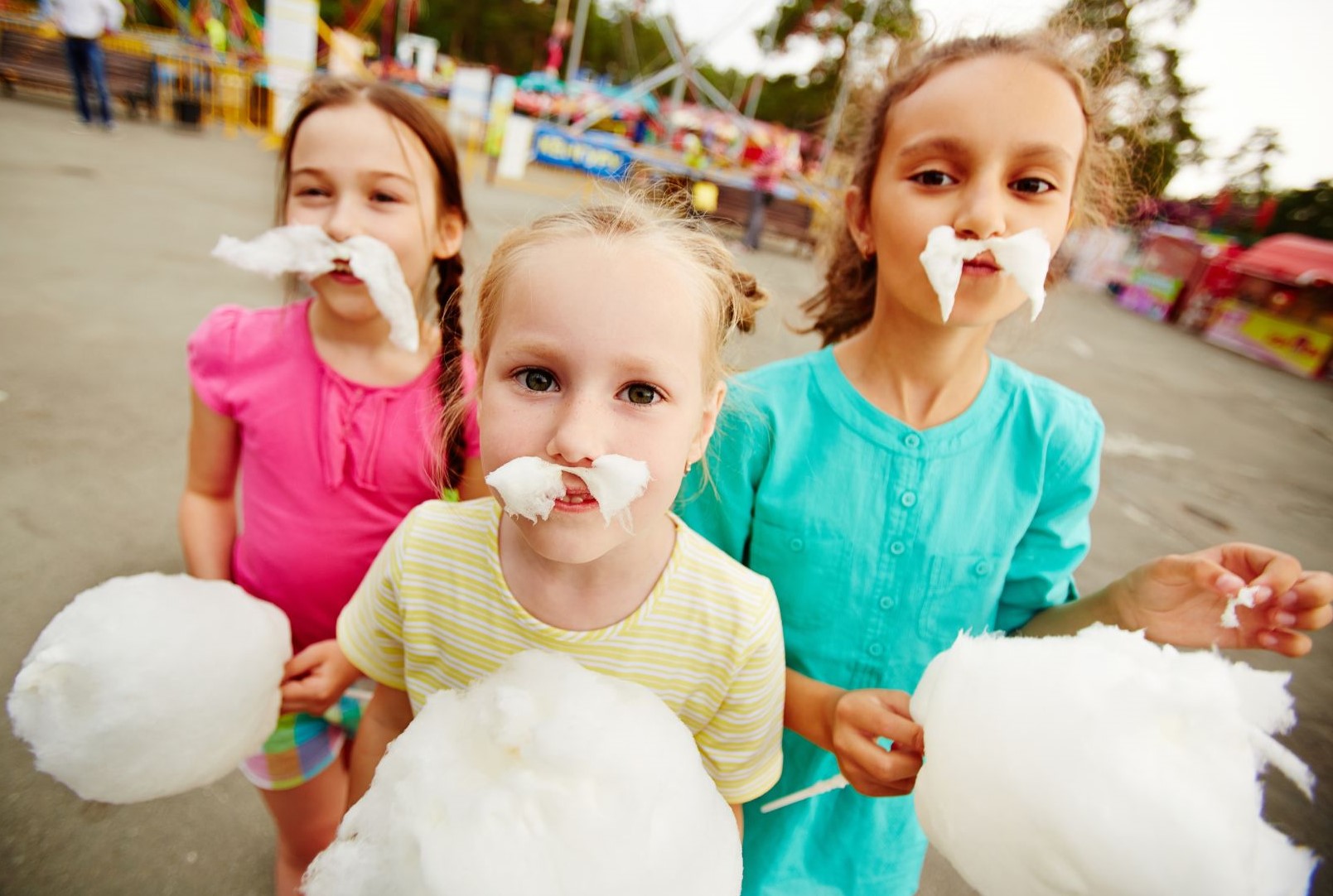 Girls eating cotton candy with bits sticking to their facse.