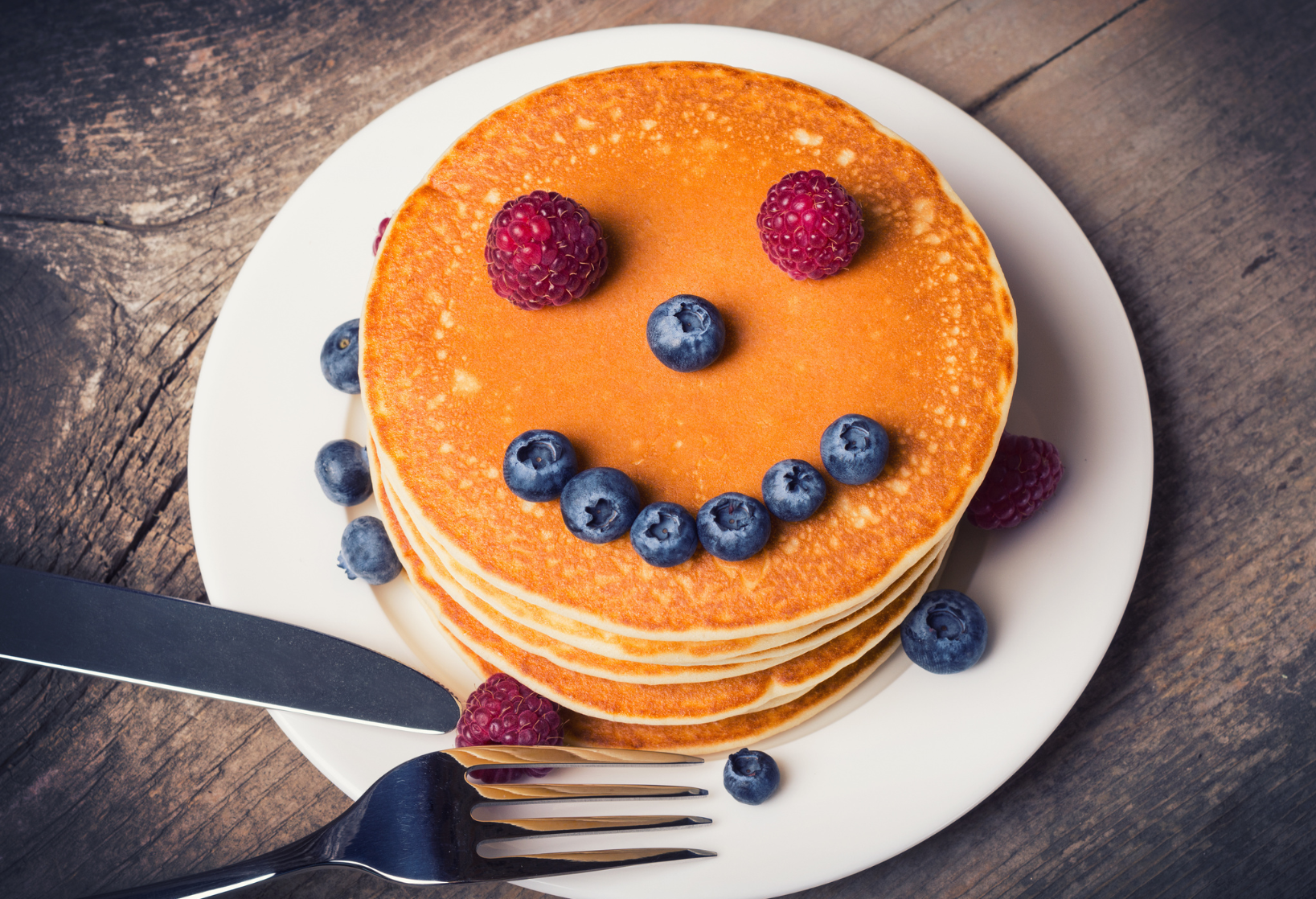 Stack of pancakes with a face made of fruit.