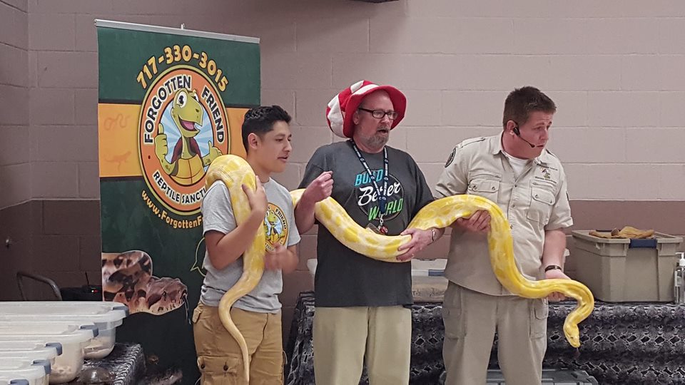 three people holding a large snake