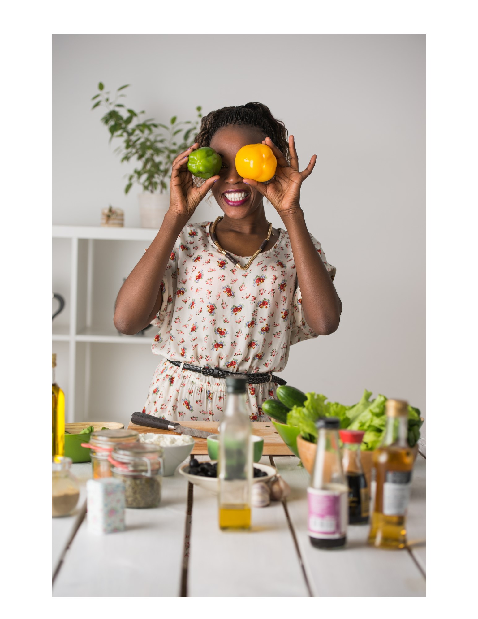 Woman in kitchen holding peppers over her eyes.