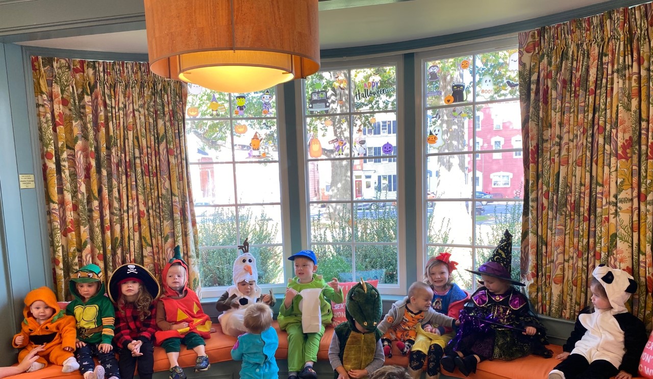 Children in various costumes sitting at a window seat