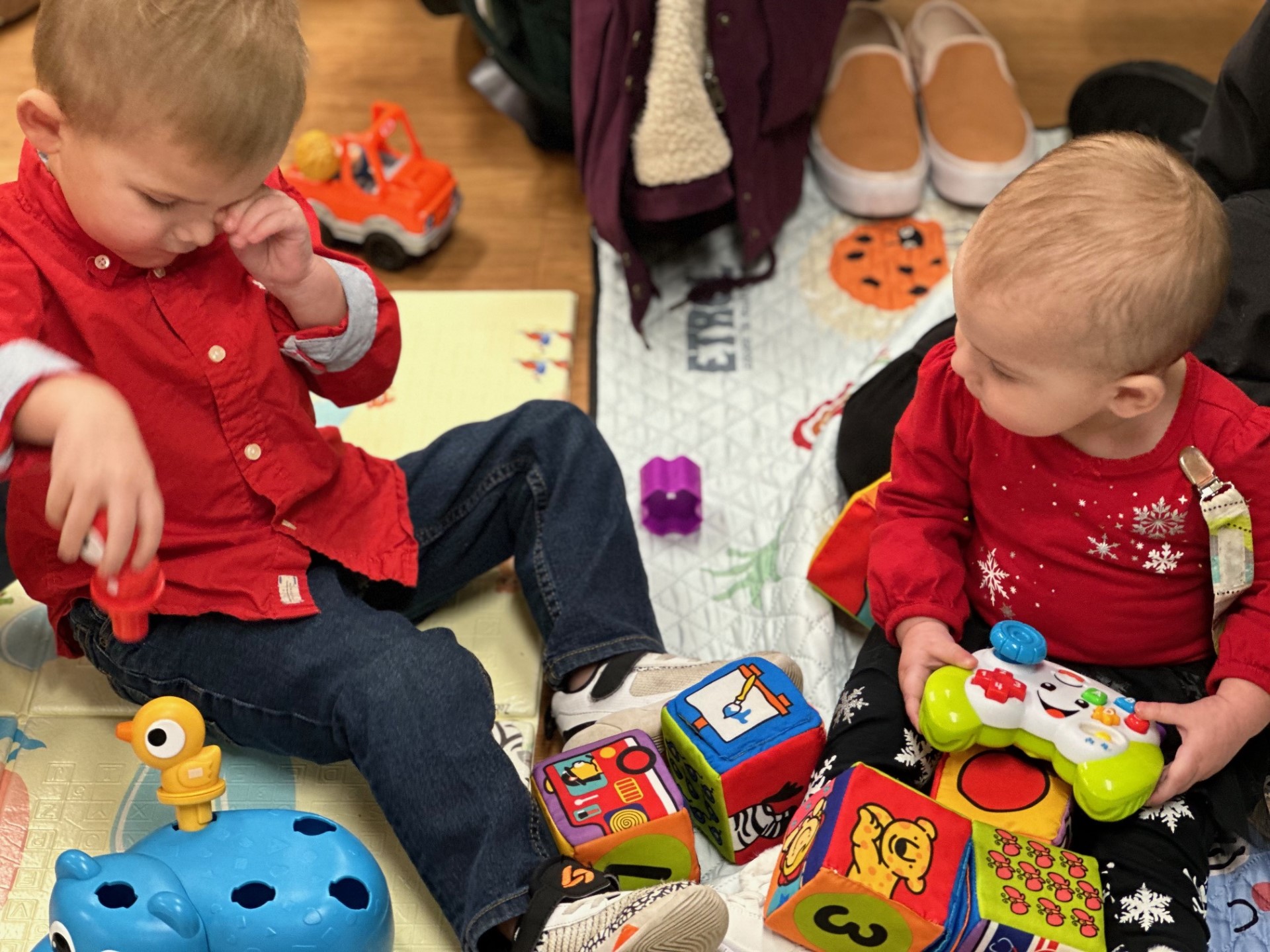 Two children wearing red shirts playing during story time.