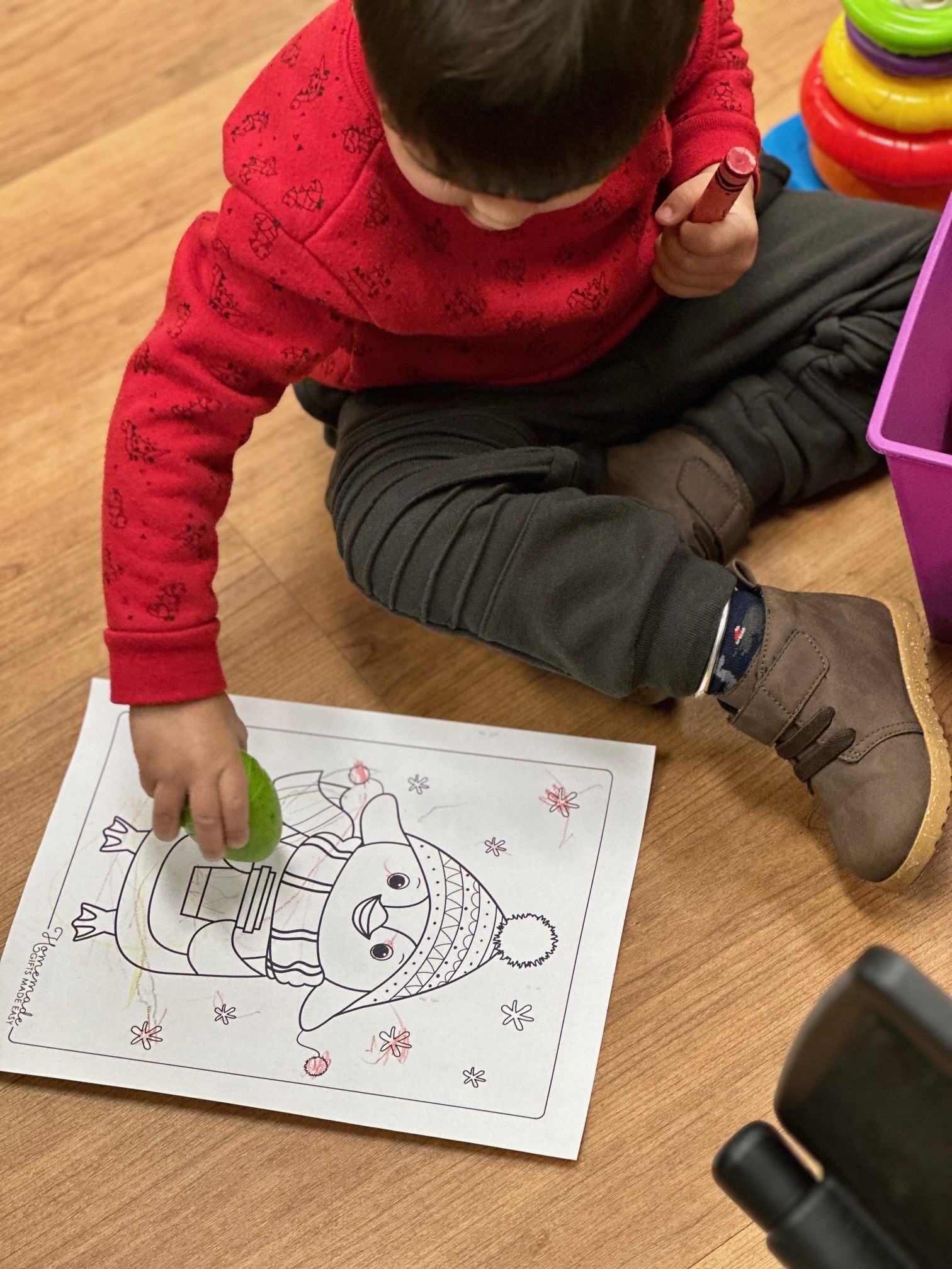 Child in red shirt coloring during story time