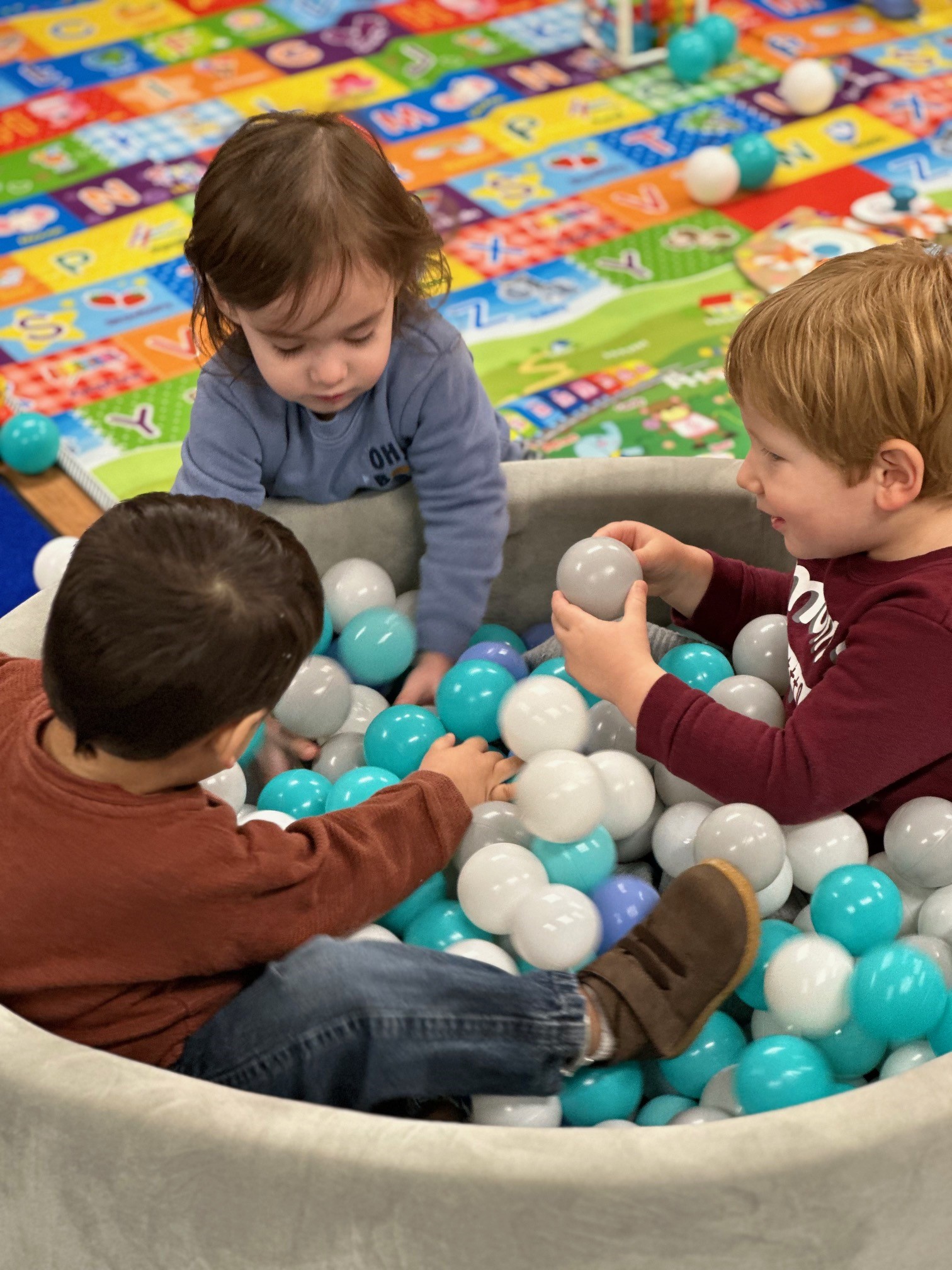 three children playing in a ball pit together. 