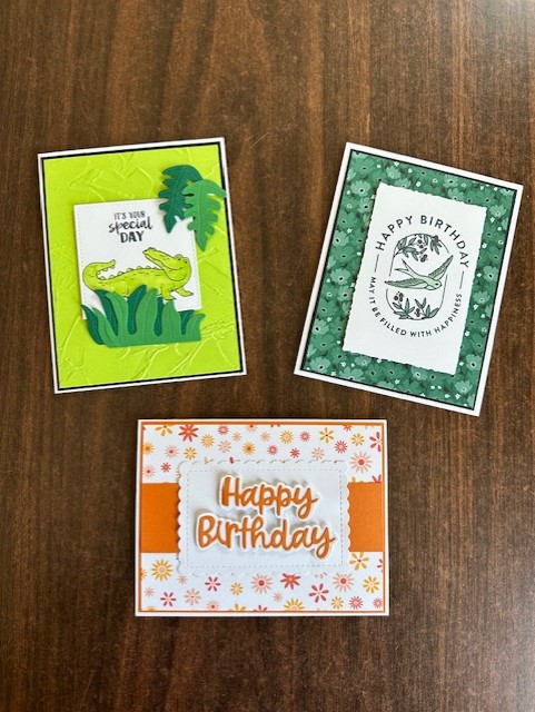 Photo featuring three cards, one is green with an alligator, another orange with happy birthday written