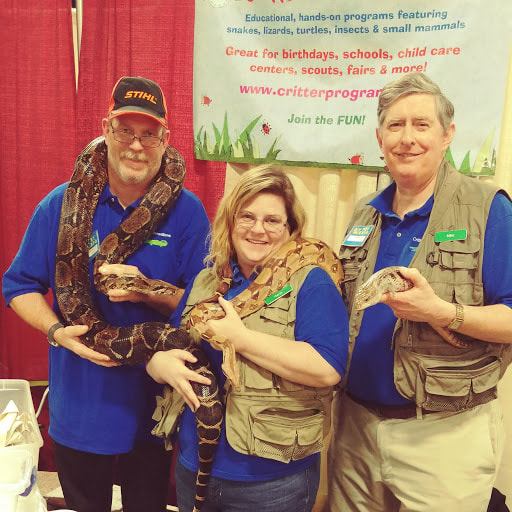three people holding snakes