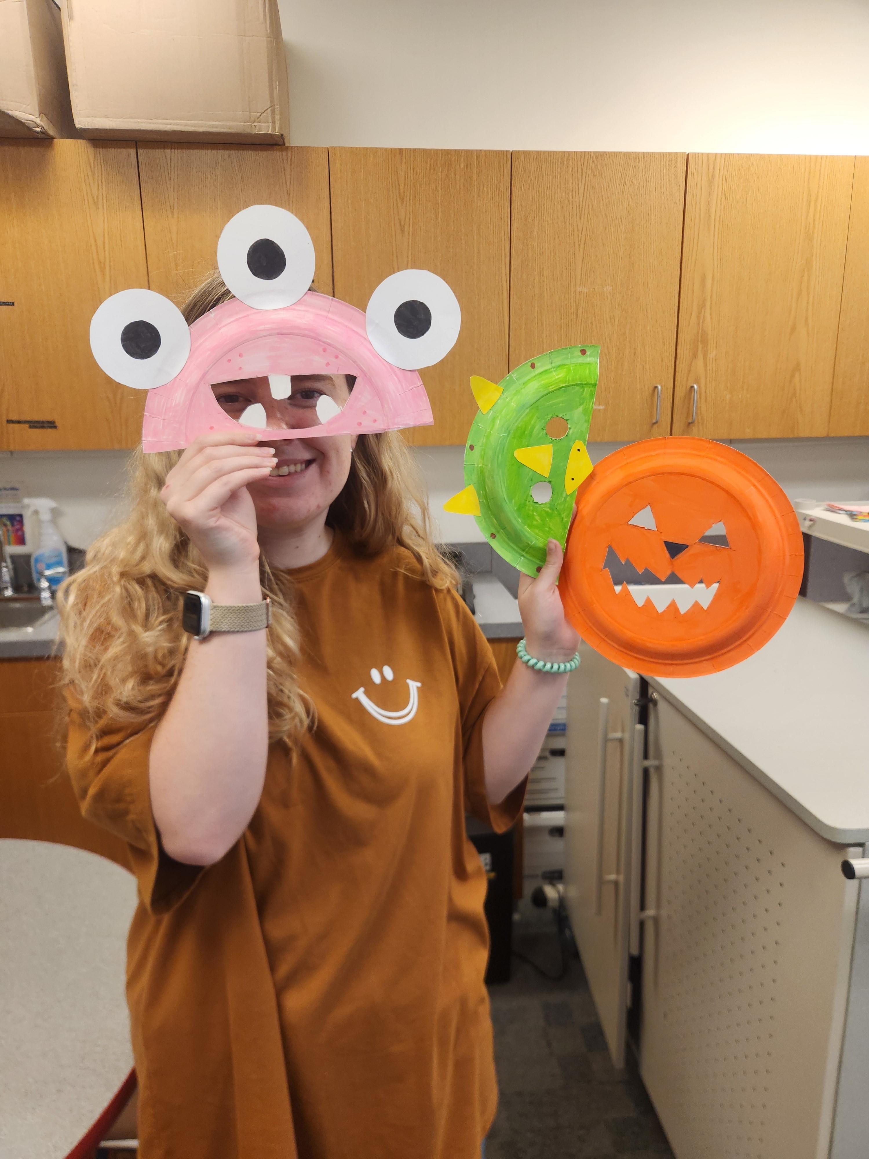 girl holding up 3 handmade paper plate masks