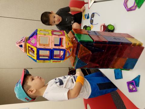 2 children playing with plastic magnetic building tiles