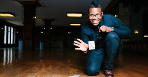 Randy Shine kneeling while doing a card trick. The card appears to be floating in front of his hand.