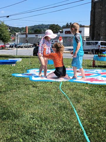 Children playing in sprinkler during water play. 