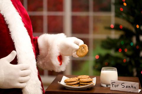 Santa taking a cookie from a tray.