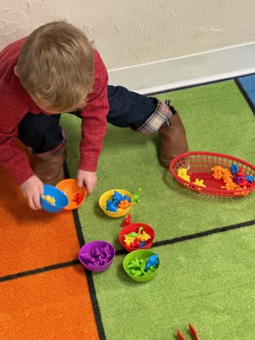 Child sorting dinosaurs during story time