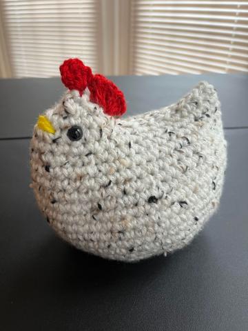 Photo of crocheted chicken with black eyes, red comb, and yellow beak