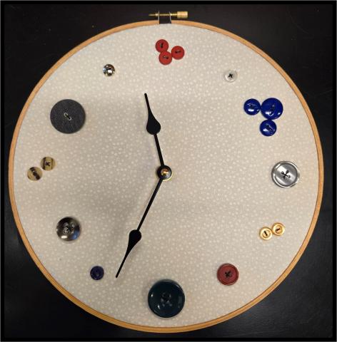 Clock made from an embroidery hoop and fabric with buttons sewn on instead of numbers