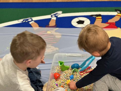 Children playing in sensory bins during story time