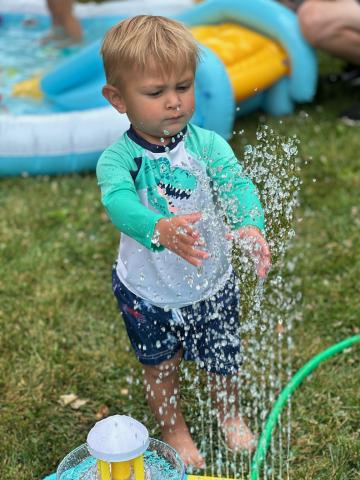 Child playing in sprinkler during water play. 