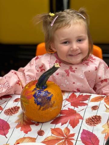 Child painting pumpkin during story time