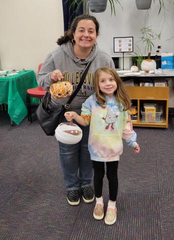 woman and girl each holding a decorated pumpkin