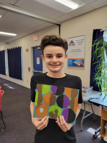 boy with dark hair holding a piece of art he made