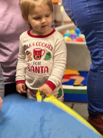 child wearing pajamas playing with parachute