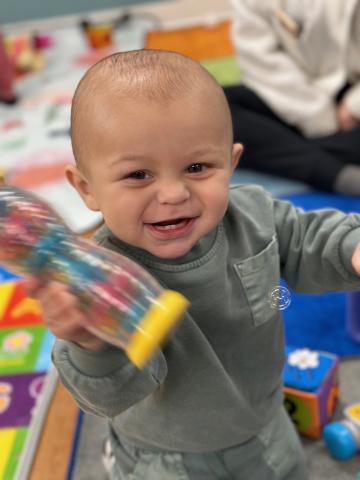 Child wearing olive green playing with shaker during story time