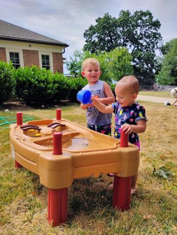 Two children playing at water table