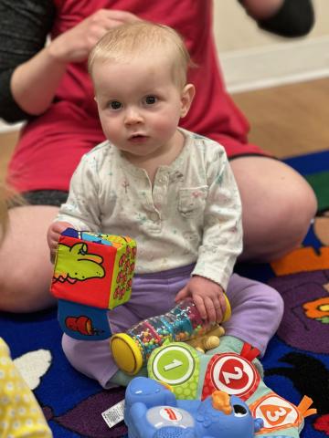 Child in white shirt playing with red block