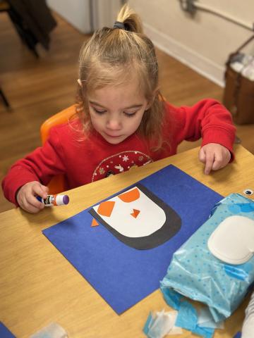 child in red shirt doing craft during story time