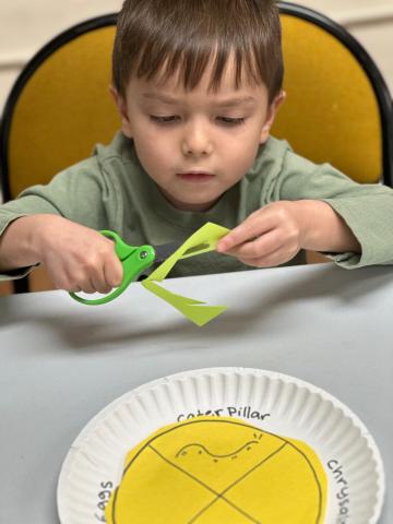 Child using scissors to cut during story time