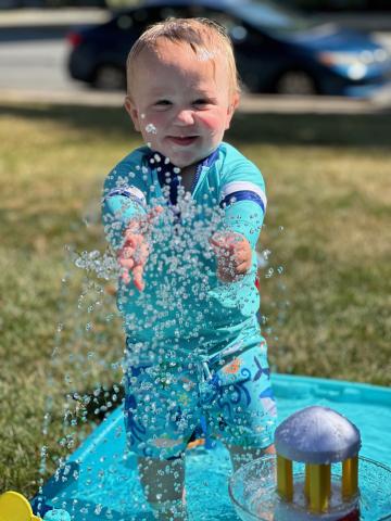 Child playing in sprinkler during water play