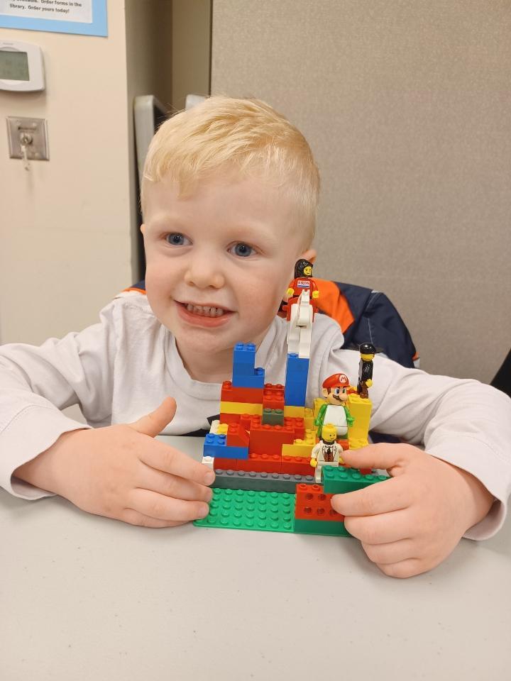 Little boy with blond hair holding Lego creation