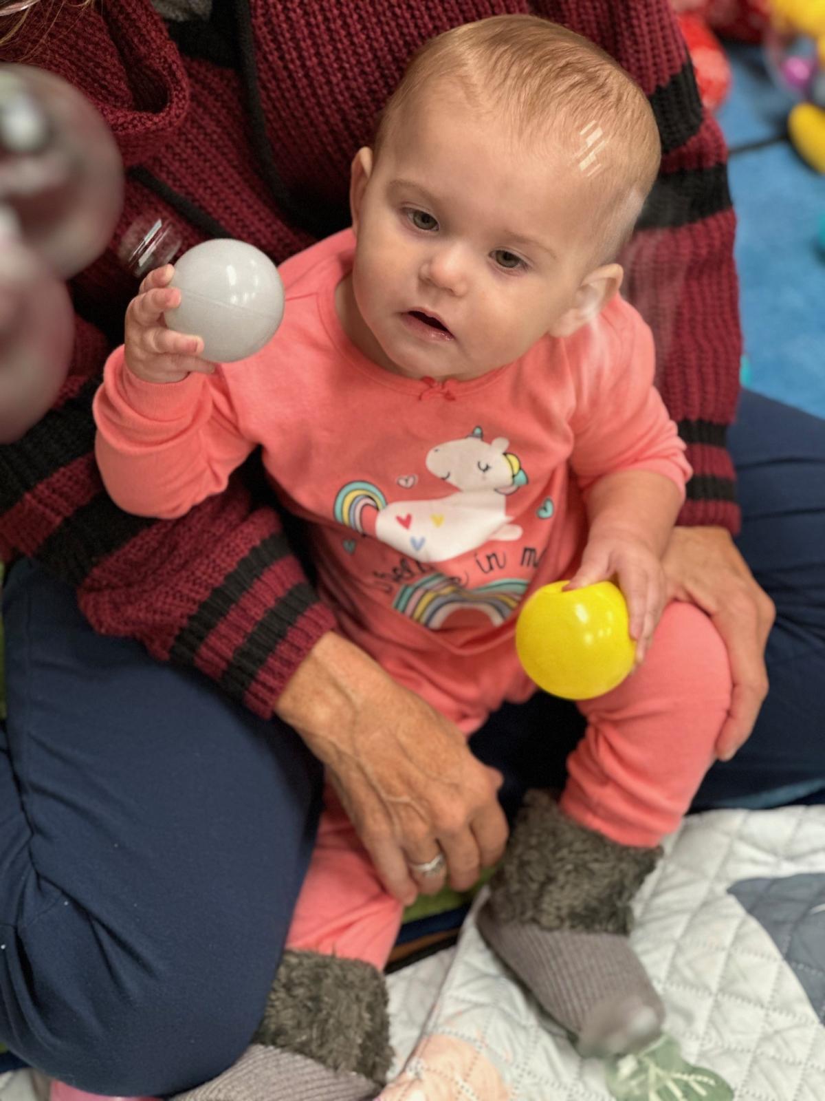 Child in pink outfit playing with a yellow and white ball