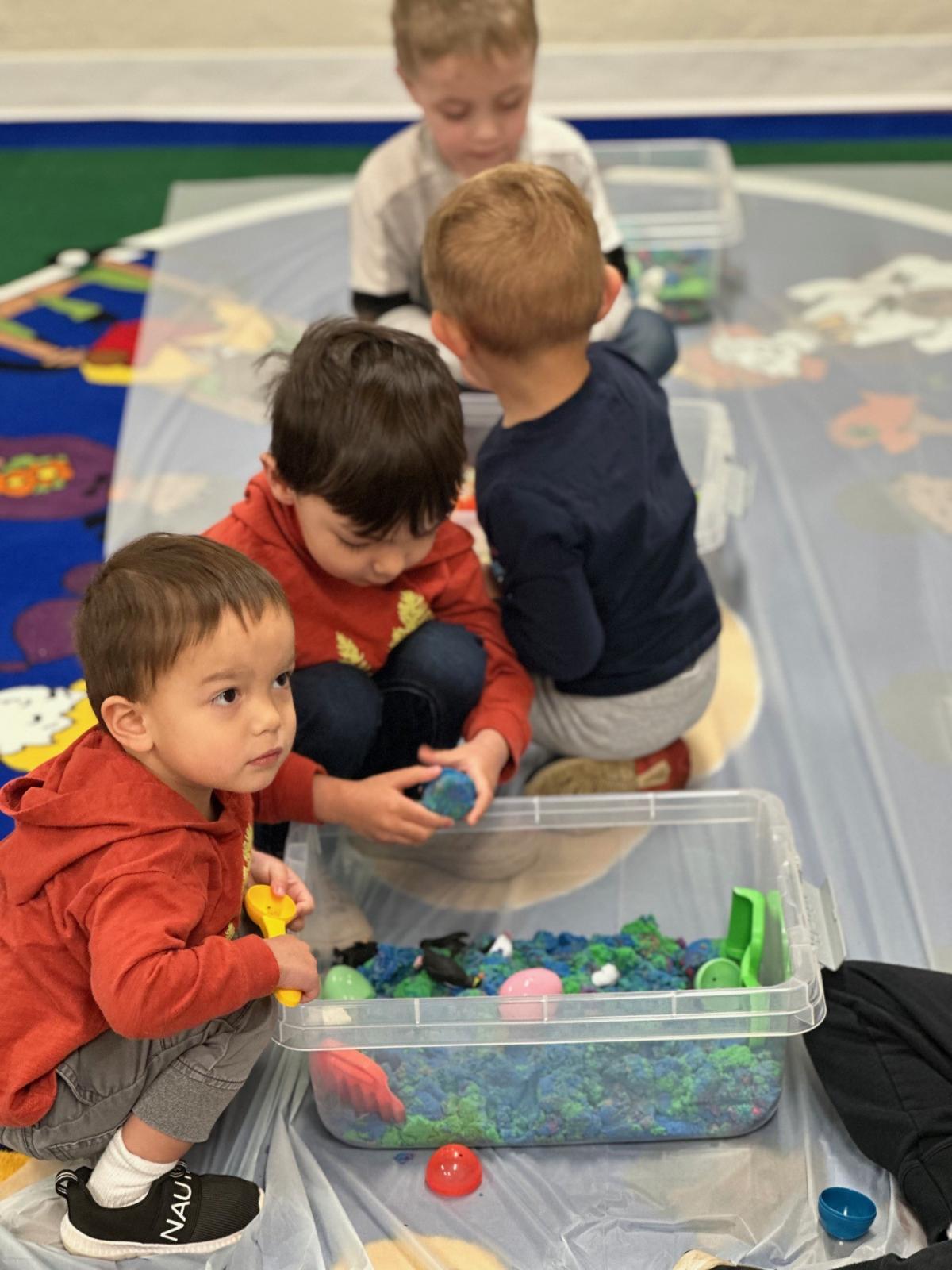 Children playing in sensory bins during story time