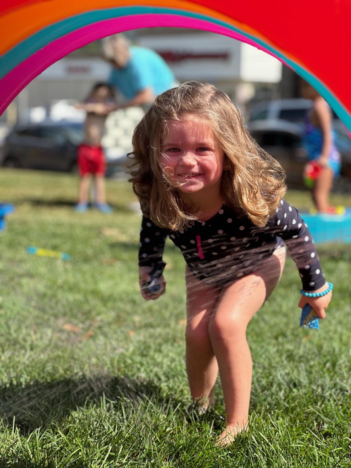 Child playing in inflatable water sprinkler during water play. 