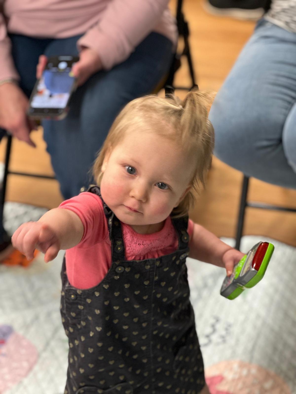 Child wearing black jumper and pink shirt popping bubbles