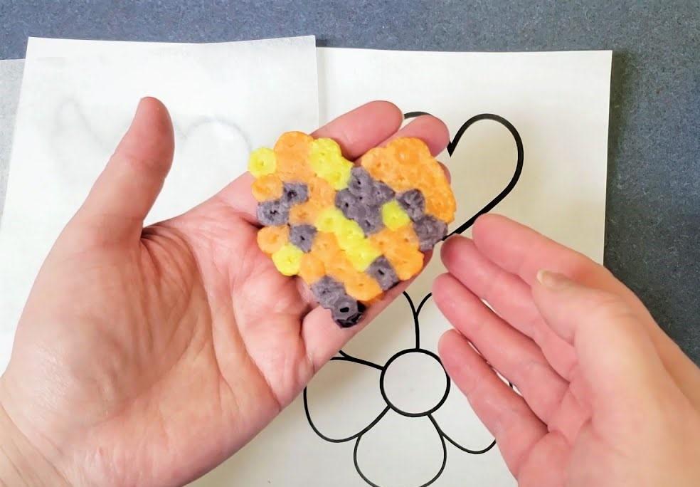 Hands holding an edible fuse bead heart.