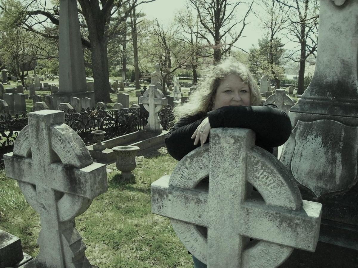 Photo of women wearing a black shirt near a gravestone in a cemetary