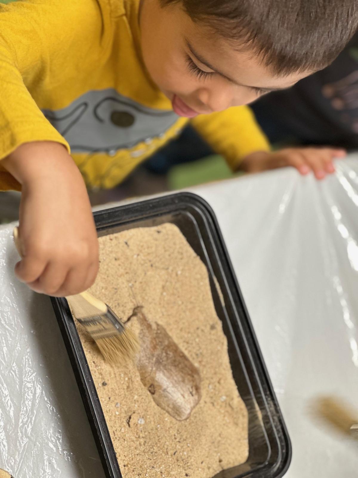 Child in yellow shirt digging for dinosaur bones