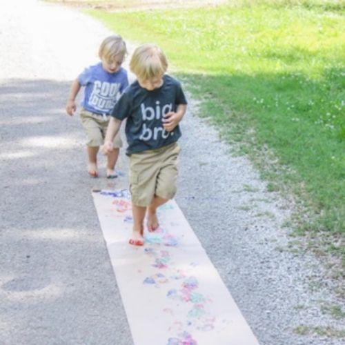 two toddlers running through paint and making footprints on paper