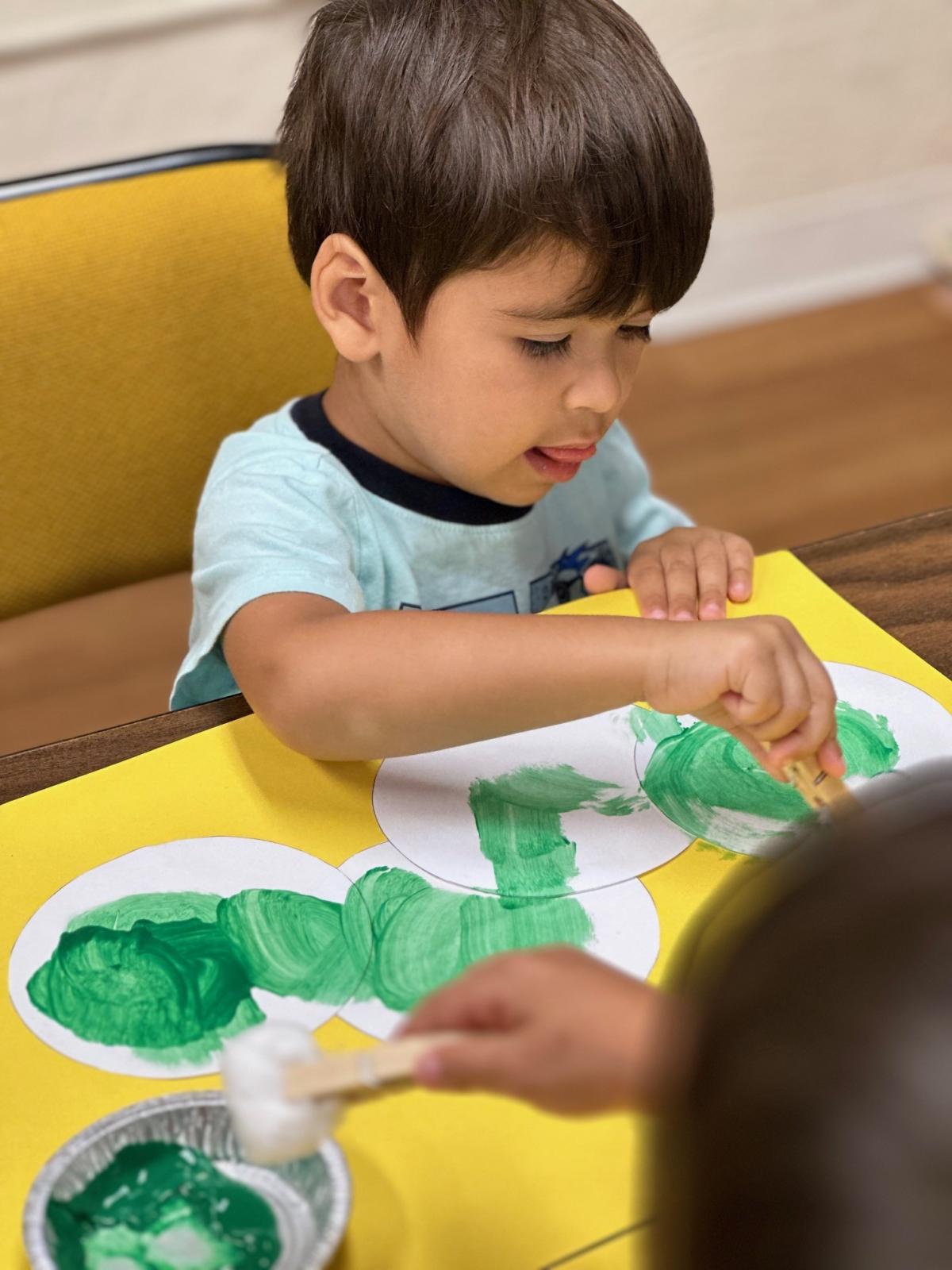 Child using green paint to make craft
