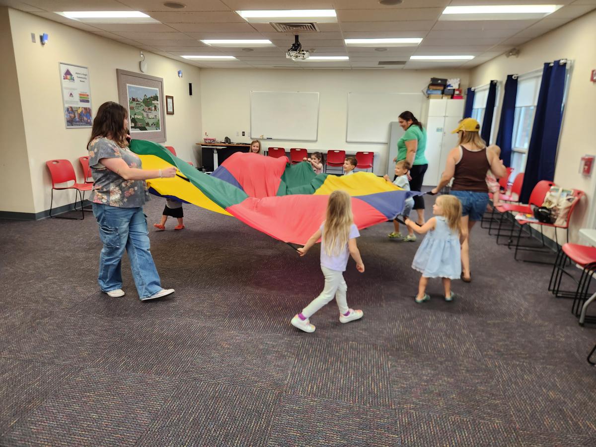 adults and children with a large colorful parachute