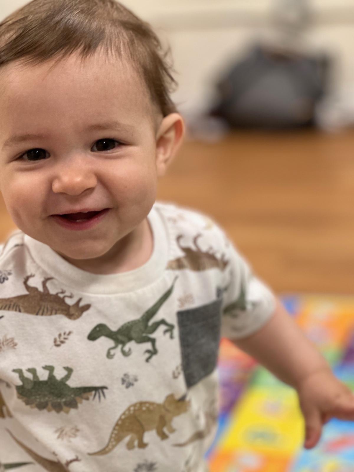 Child wearing dinosaur shirt smiling